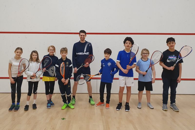 Jugendliche stehen mit Squash-Racket in der Squash-Halle